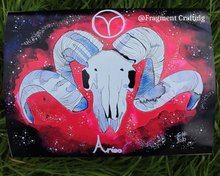 Load image into Gallery viewer, A print copy on grass of Aries star sign painting of a red and purple background with a white Ram&#39;s skull.
