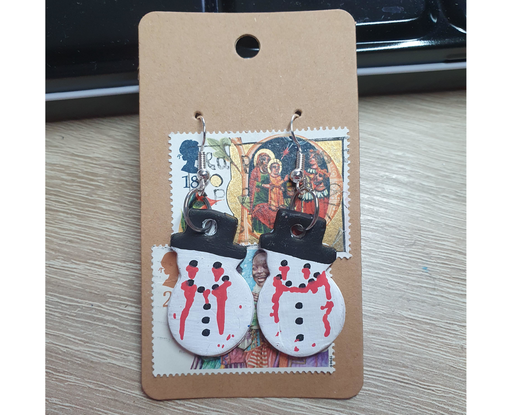A pair of white snowman goth earrings with running blood.