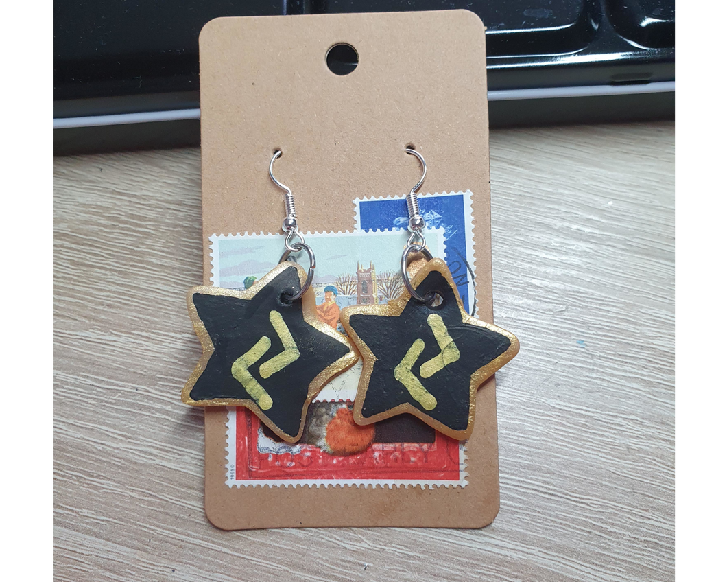 A pair of gold and black clay star earrings.