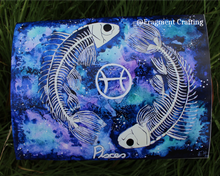 Load image into Gallery viewer, A print copy of a Pisces star sign watercolour painting with a green and purple background and two white fish skeletons being showcased on the grass.
